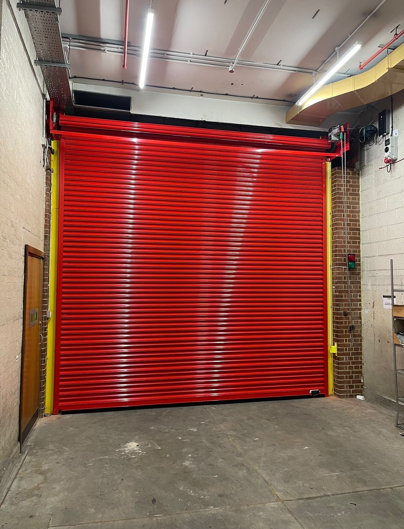 Red fire rated roller shutter installed in a commercial building opening
