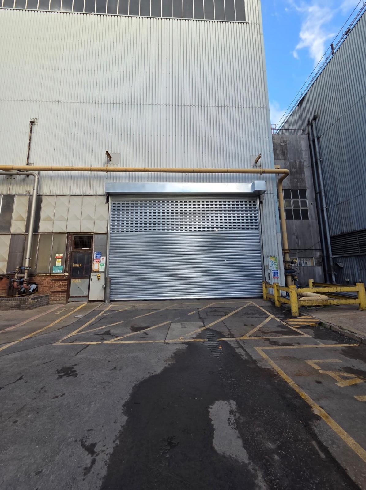 Silver warehouse roller shutter with yellow safety bollards