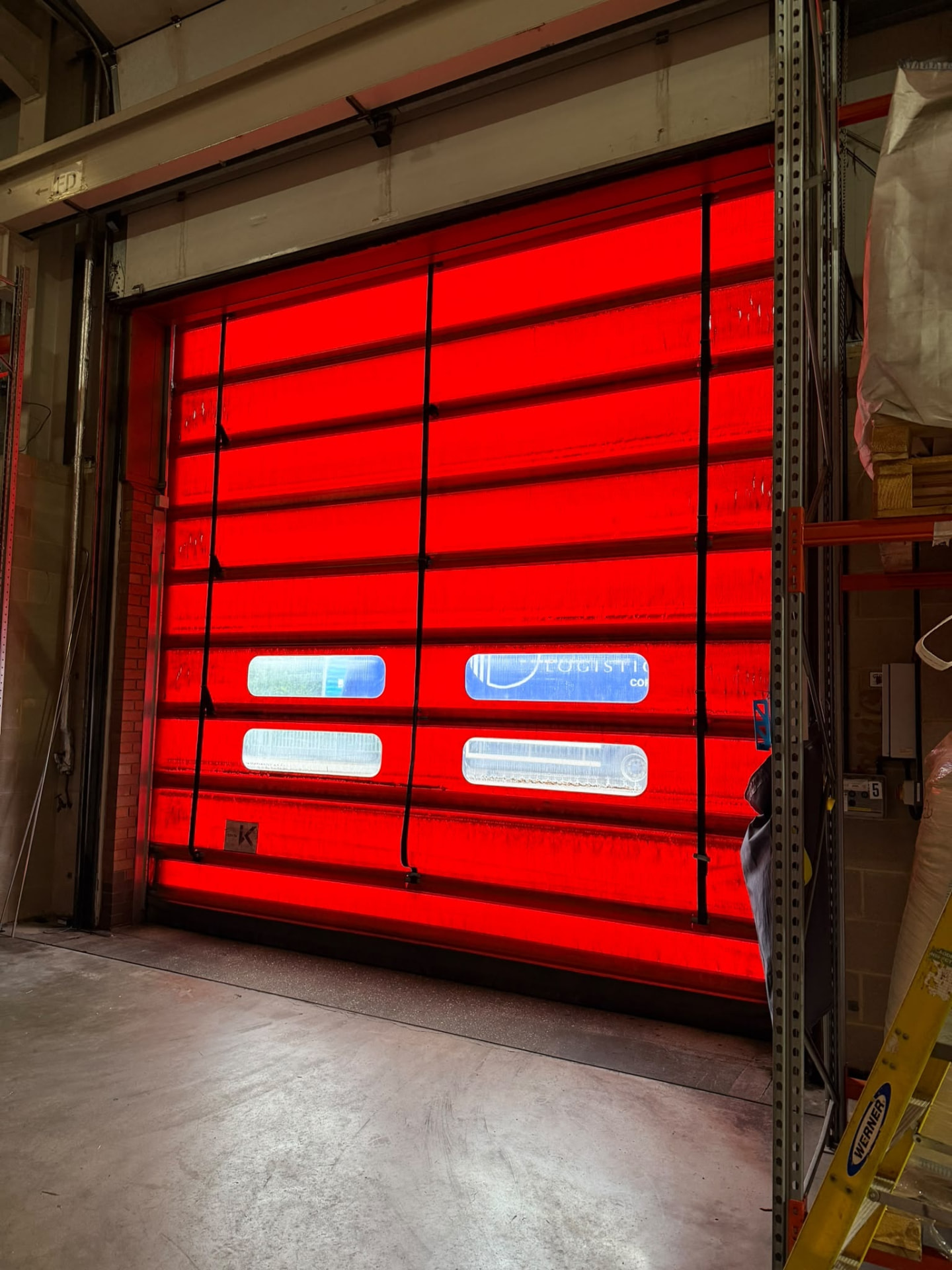 Red high speed industrial door viewed from a warehouse interior