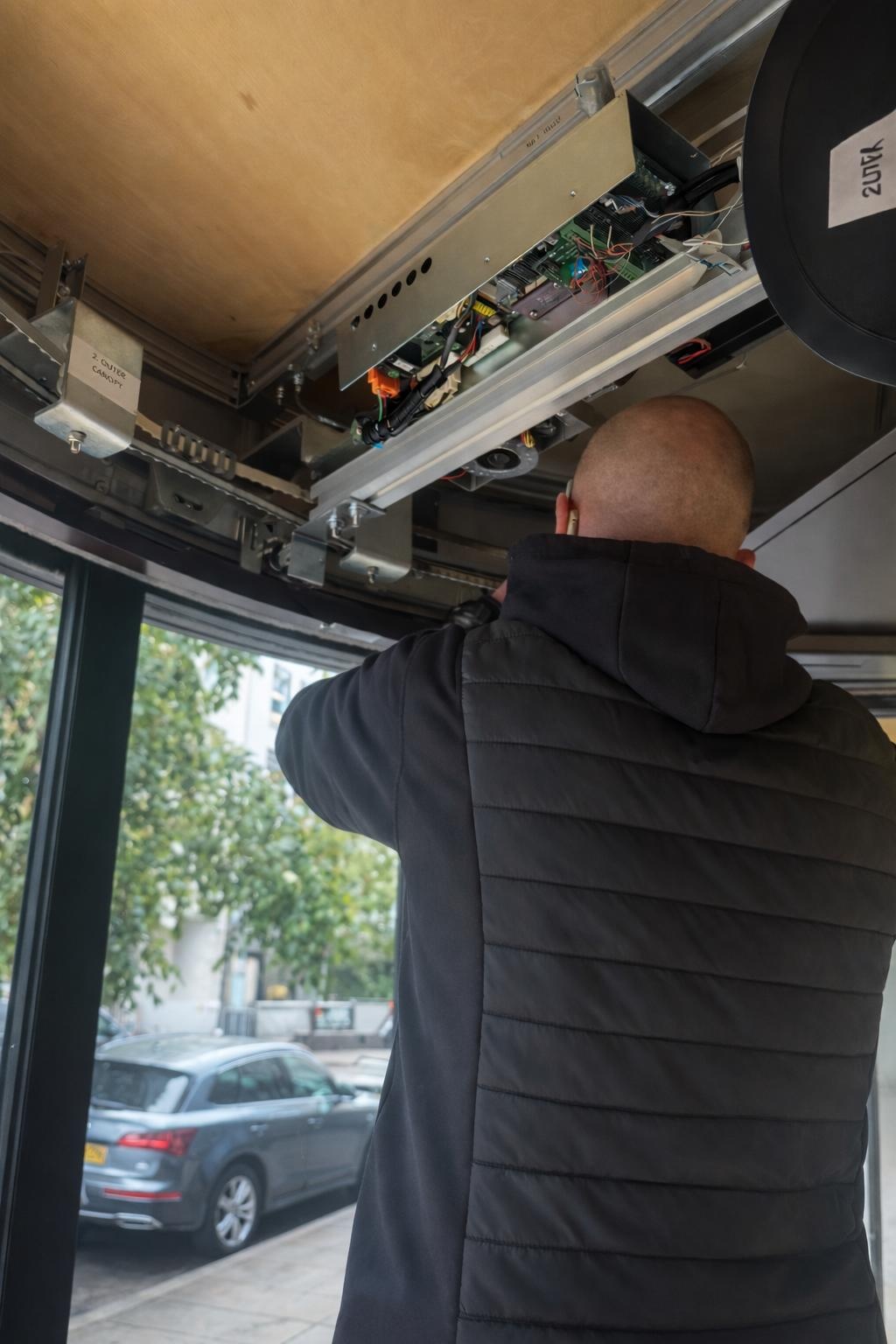 Engineer testing an automatic door operator above a shop entrance